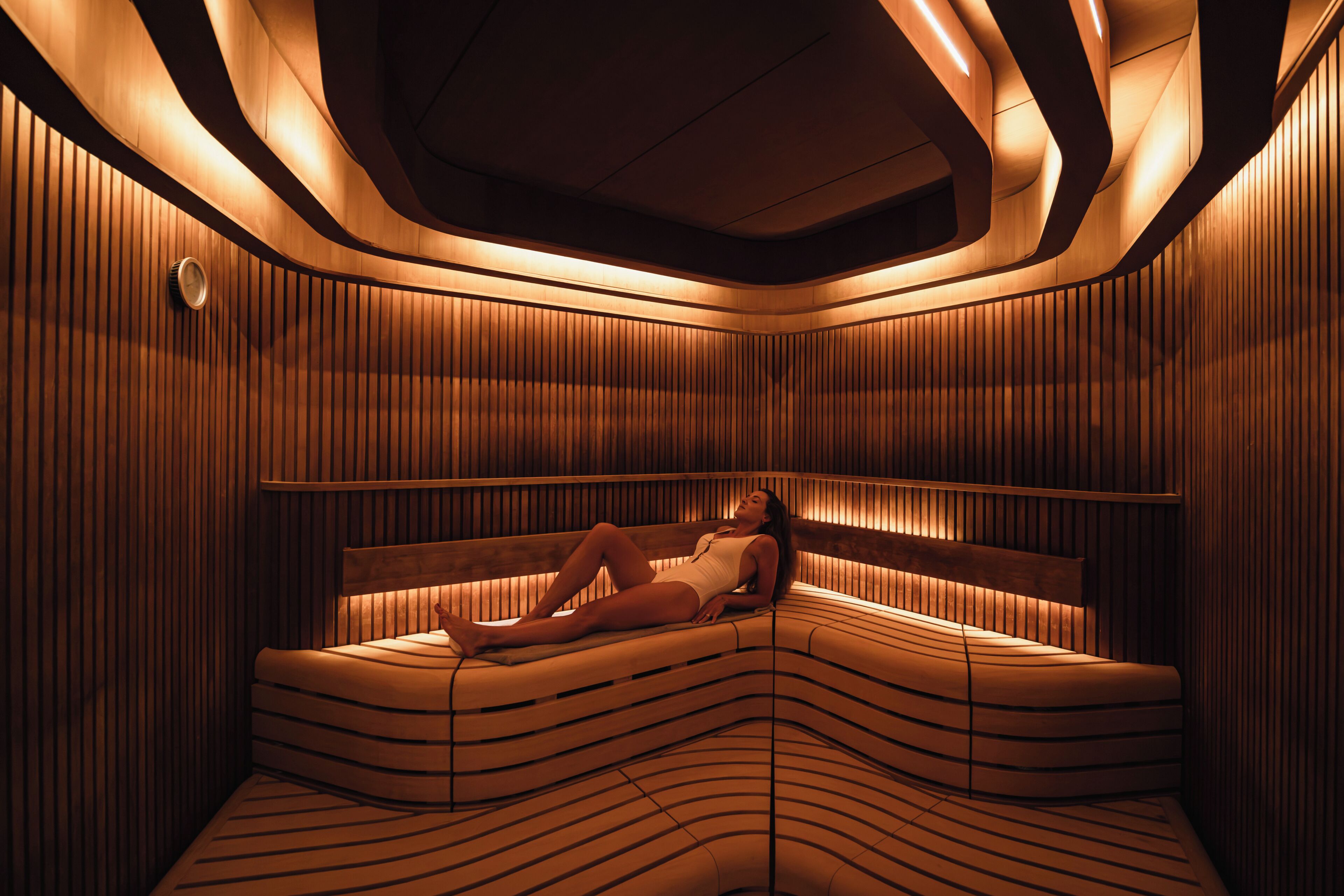 A sauna with a curved bench and wooden paneling.