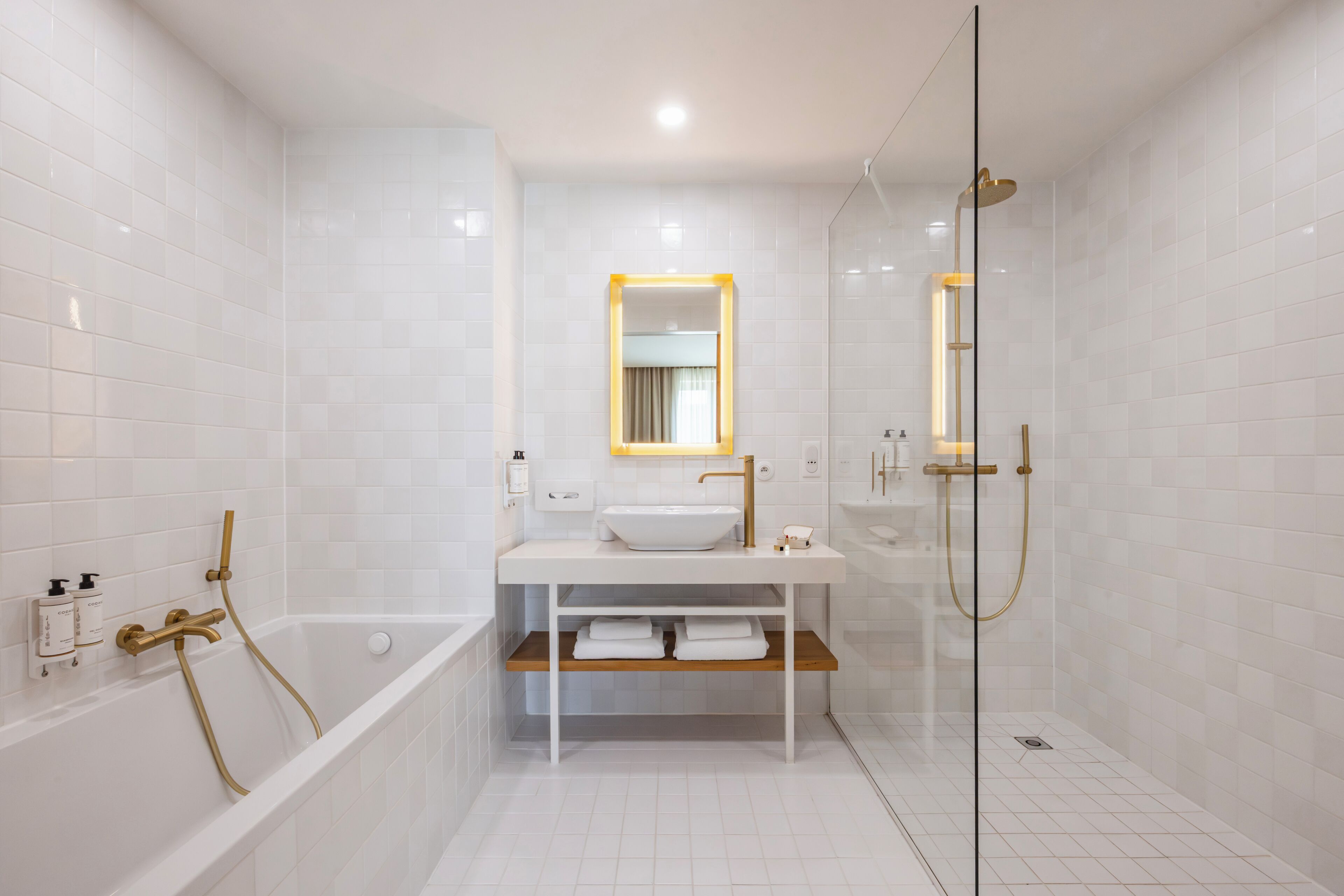 A modern bathroom with a bathtub, a glass-enclosed shower, and a vanity with a sink and mirror.
