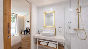 Un baño moderno con tocador blanco, un espejo grande y grifería de ducha dorada.