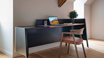 A modern office space with a desk, chair, laptop, and a vase with flowers.