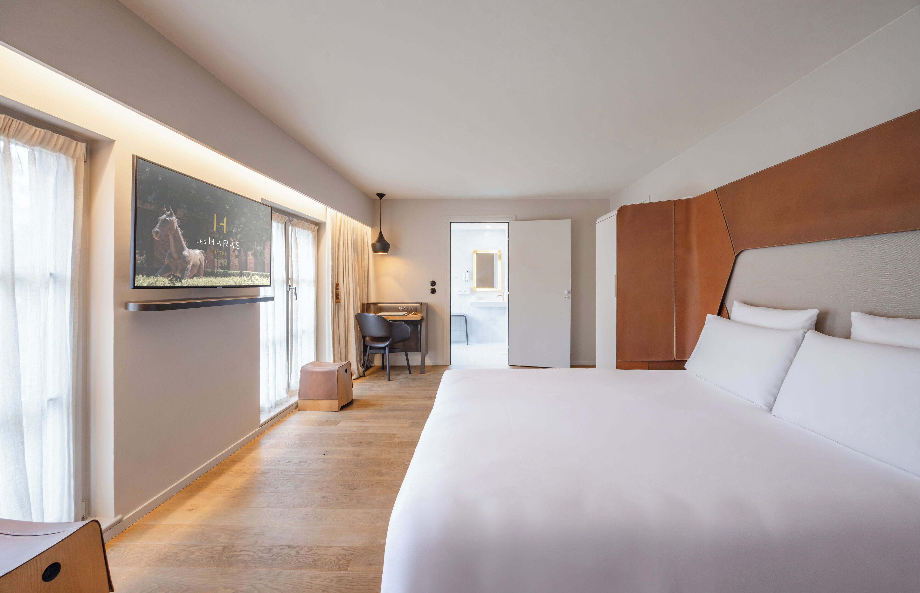 A hotel room with a large bed, a desk, and a television on the wall.