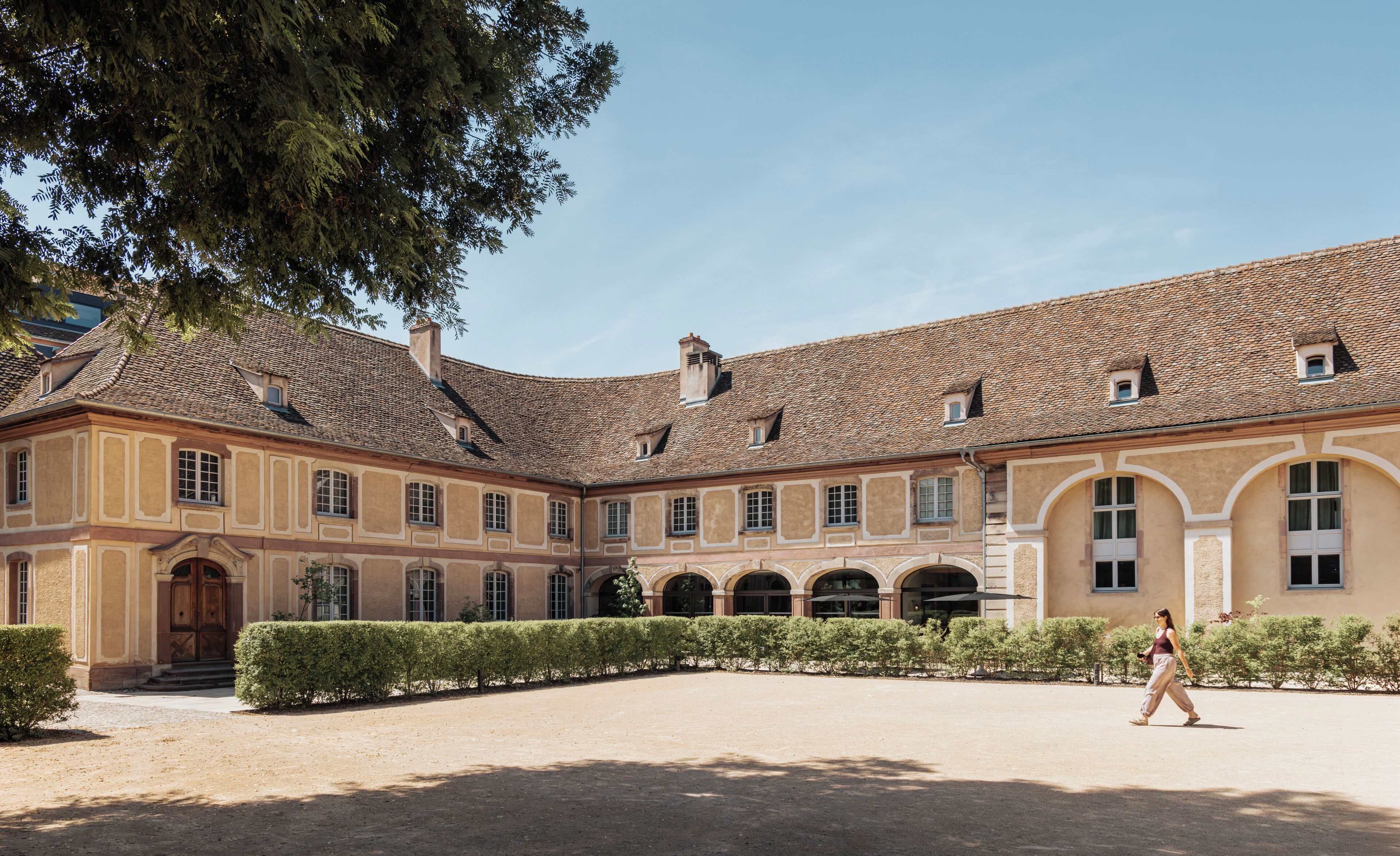 A courtyard with a building featuring a tiled roof and arched windows.