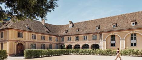 A courtyard with a building featuring a tiled roof and arched windows.