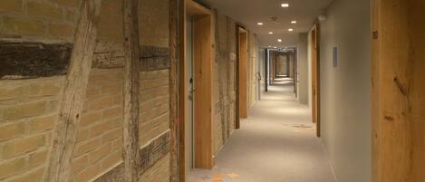 A long, narrow hallway with exposed brick walls and wooden doors.