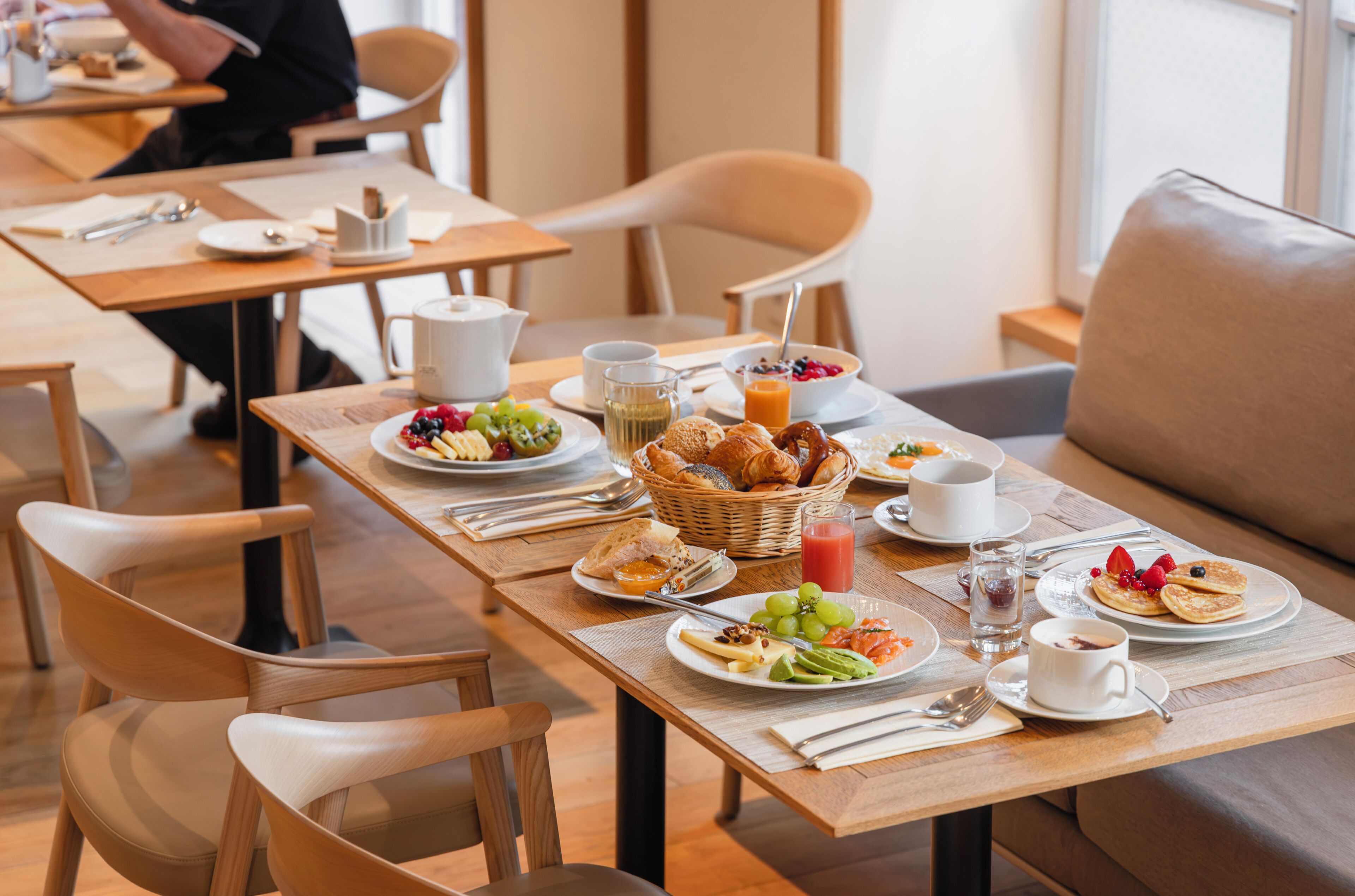 A breakfast setting with tables, chairs, and a variety of food items.