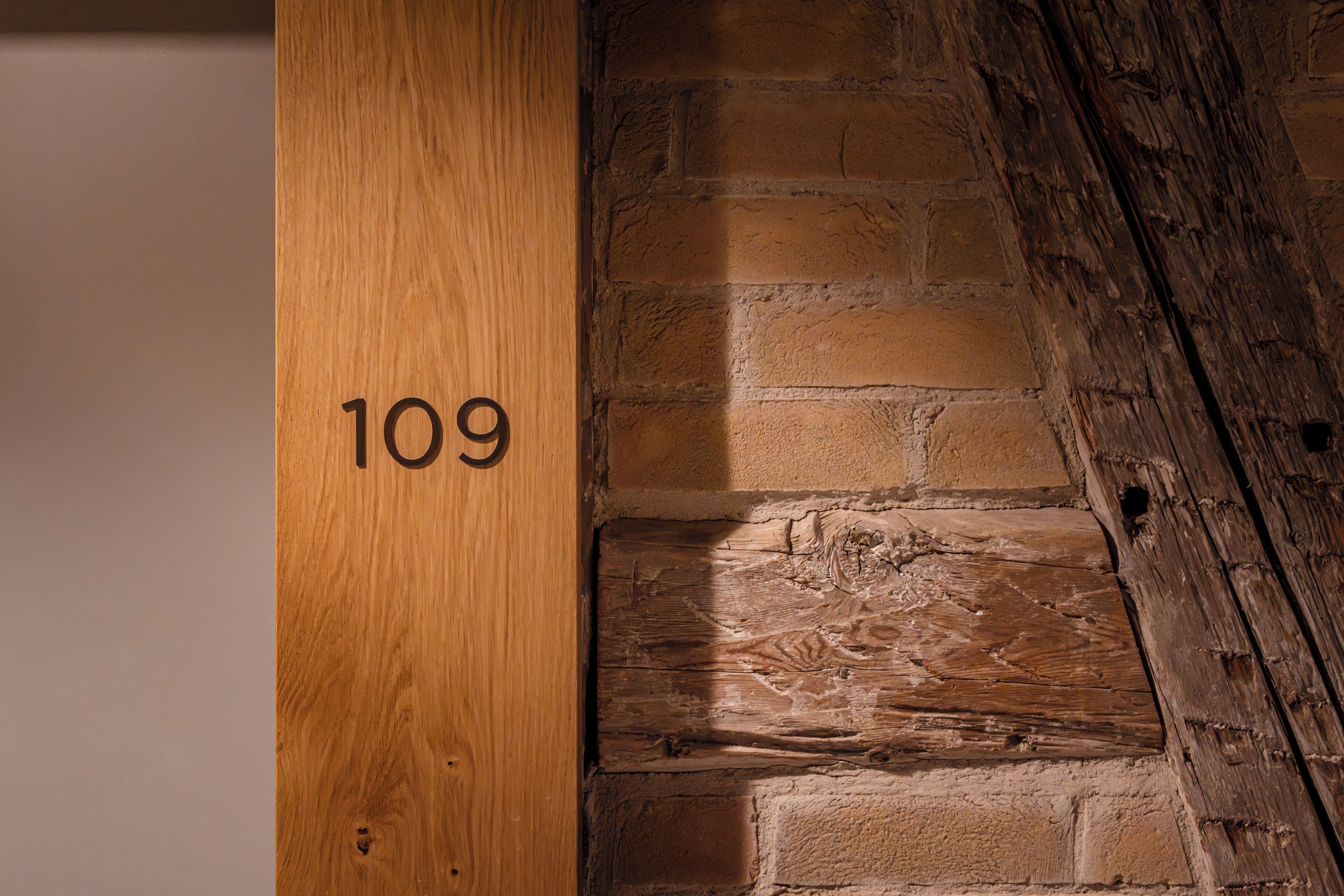Ein Holzmast mit der Nummer 109, eine Ziegelwand und ein Holzbalken.
