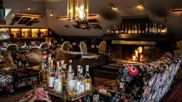 Un área de bar con chimenea, asientos y una variedad de botellas sobre una bandeja.