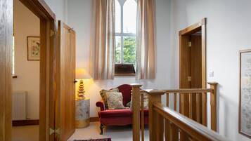 Una habitación acogedora con un sillón rojo, una escalera de madera y una ventana con cortinas.