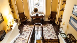 A room with a high arched ceiling, a large stained glass window, and a staircase with a floral carpet. - Augill Castle (Kirkby Stephen)