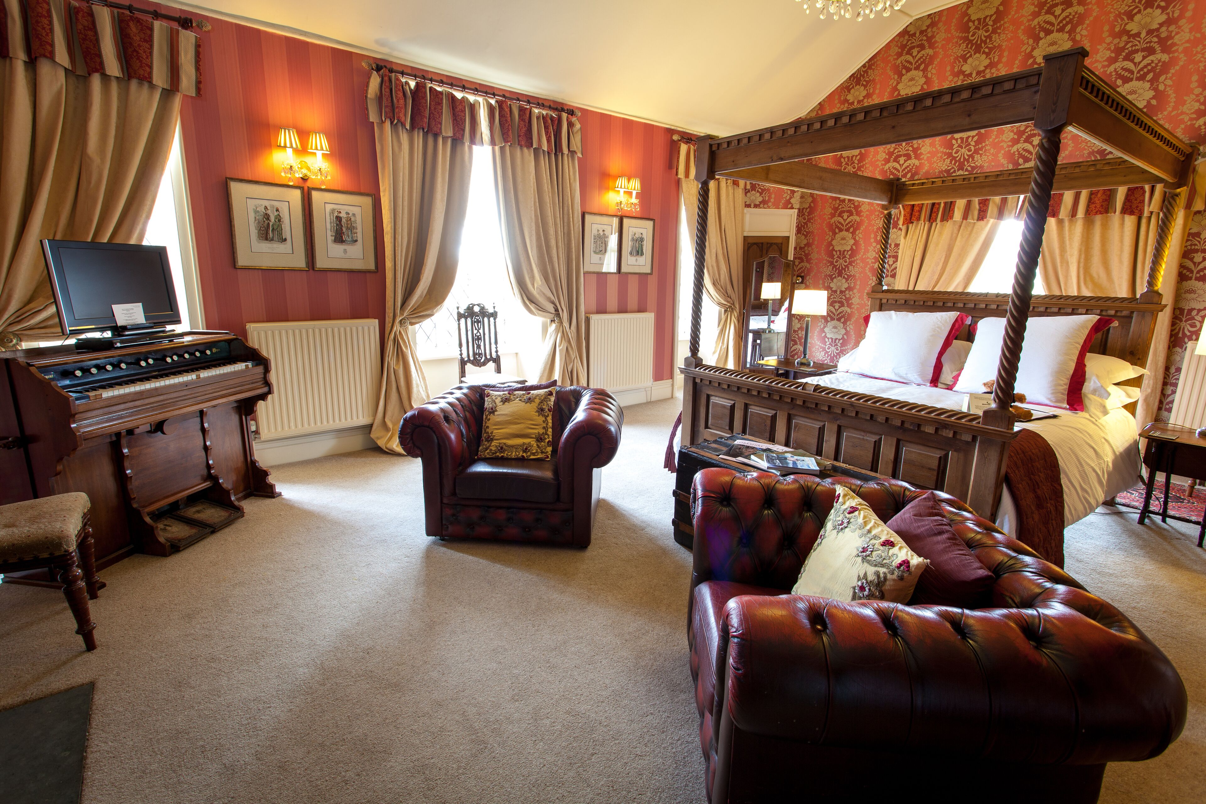 Ein traditionell eingerichtetes Schlafzimmer mit Himmelbett, Klavier, Ledersessel und Sofa.