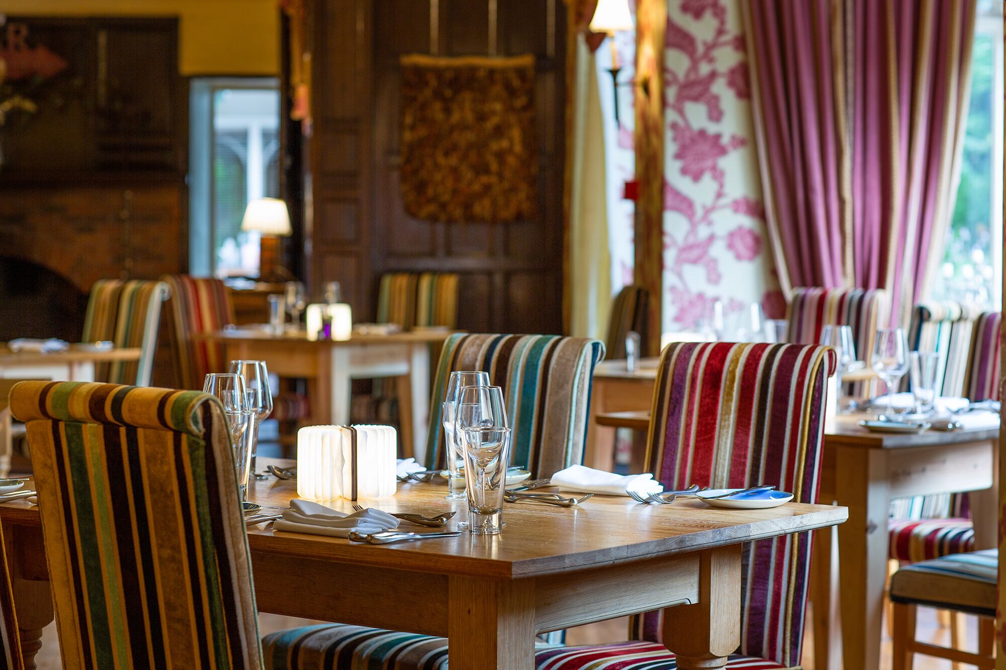 A restaurant interior with striped chairs, wooden tables, and a warm ambiance.