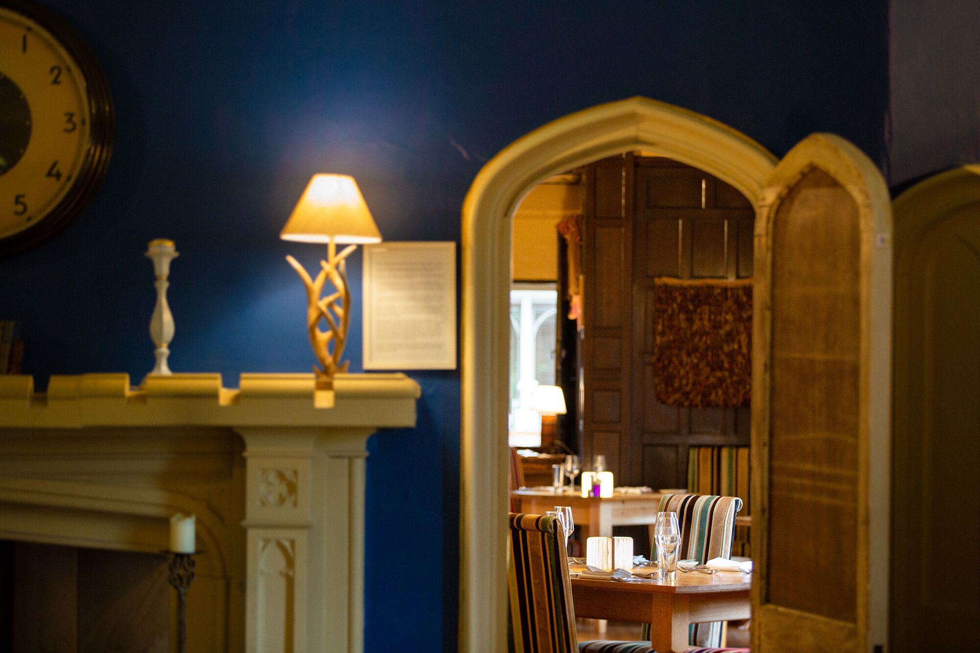 A room with a fireplace, a table set for dining, and a clock on the wall.