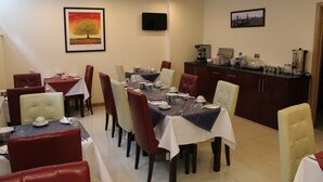 A dining area with multiple tables set for service, a coffee station, and framed artwork on the walls. - Regency Hotel Parkside (London)