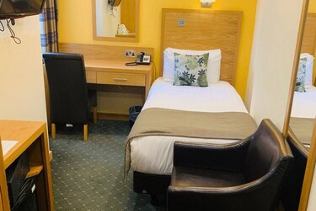 A hotel room with a bed, a desk, a chair, a television, and a mirror.
