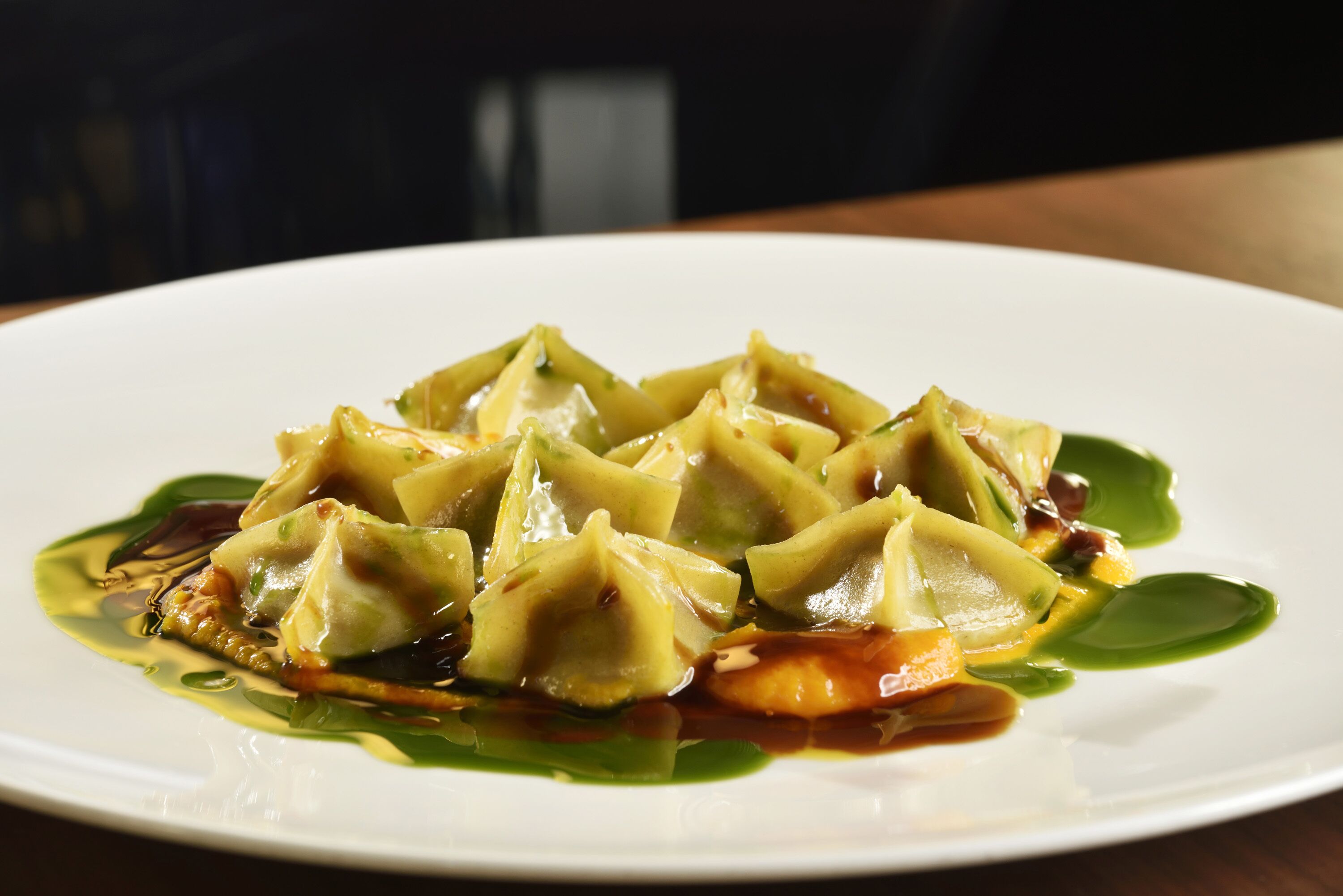 Un piatto di gnocchi con salsa verde e verdure.