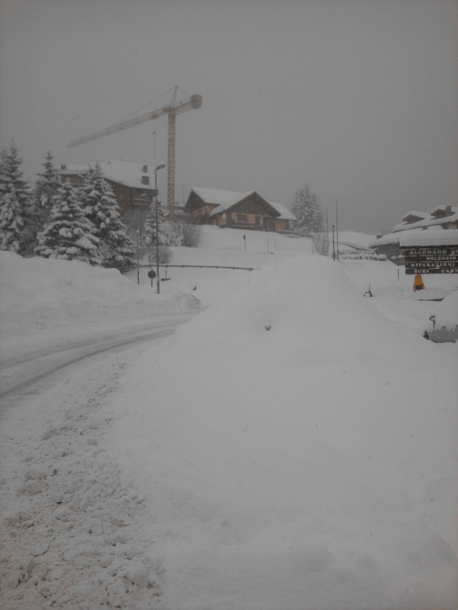 Una carretera cubierta de nieve con una cabaña de madera y una grúa de construcción al fondo.