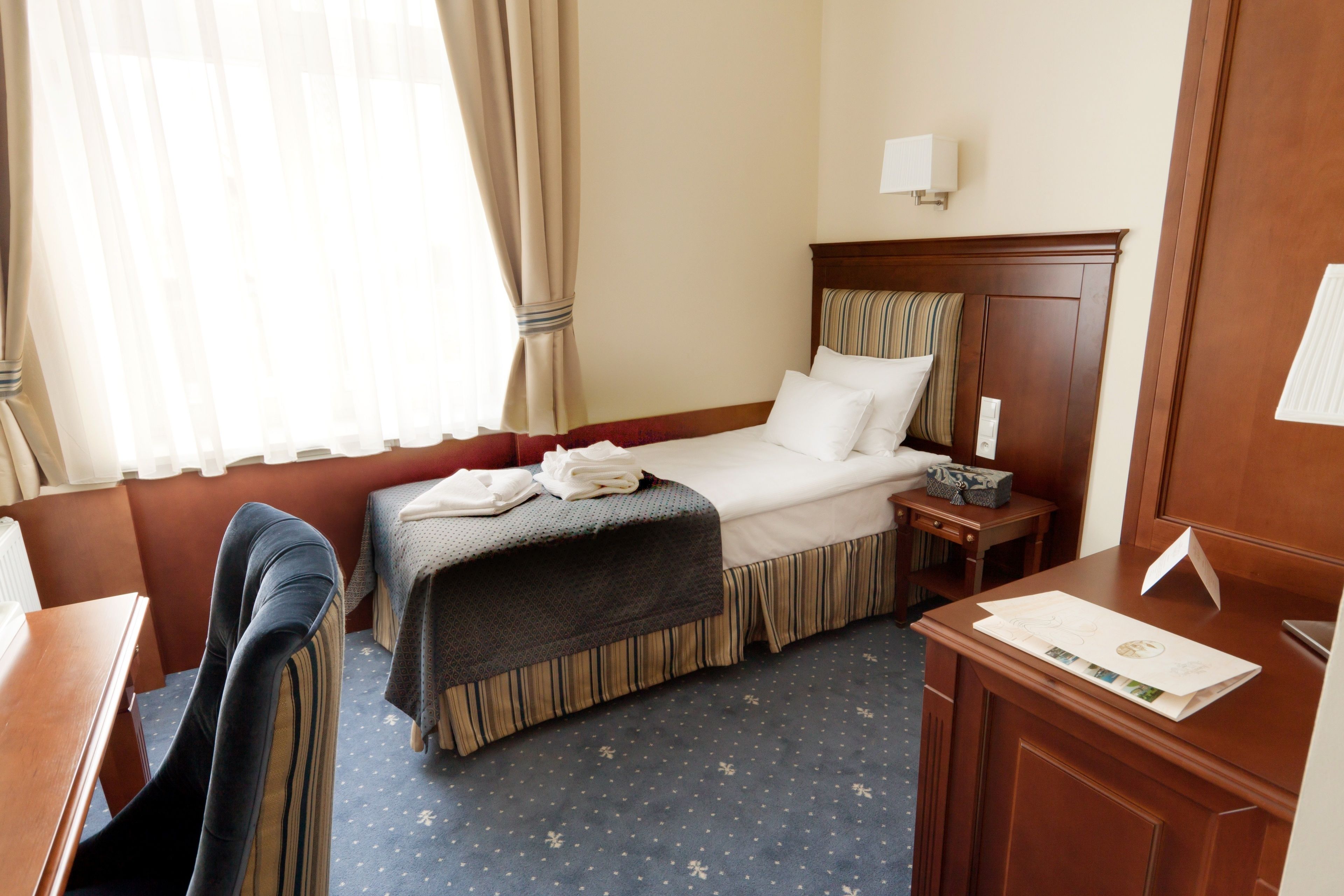 Une chambre d’hôtel comprenant un lit, une table de chevet, une lampe et un bureau avec une chaise.