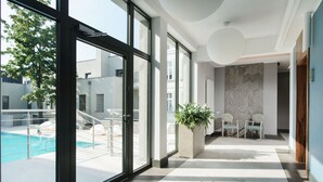 A modern hotel lobby with a large glass door leading to a pool area. - Palac Romantyczny (Lysomice)
