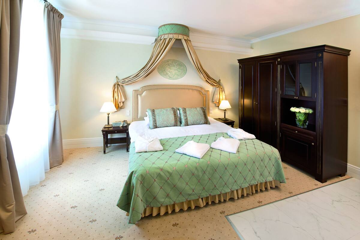 A hotel room with a large bed, a nightstand, a dresser, and a canopy bed.