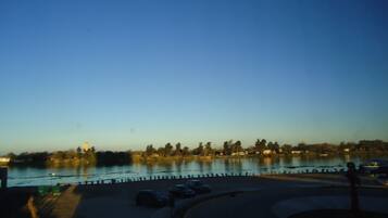 A waterfront view with a dock, parked cars, and a clear sky.