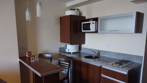 Una cocina compacta con microondas, pileta y muebles de madera.