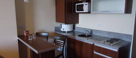 A compact kitchen with a microwave, sink, and wooden cabinets.