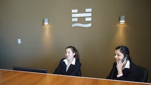 Un mostrador de recepción con dos personas sentadas detrás, conversando.