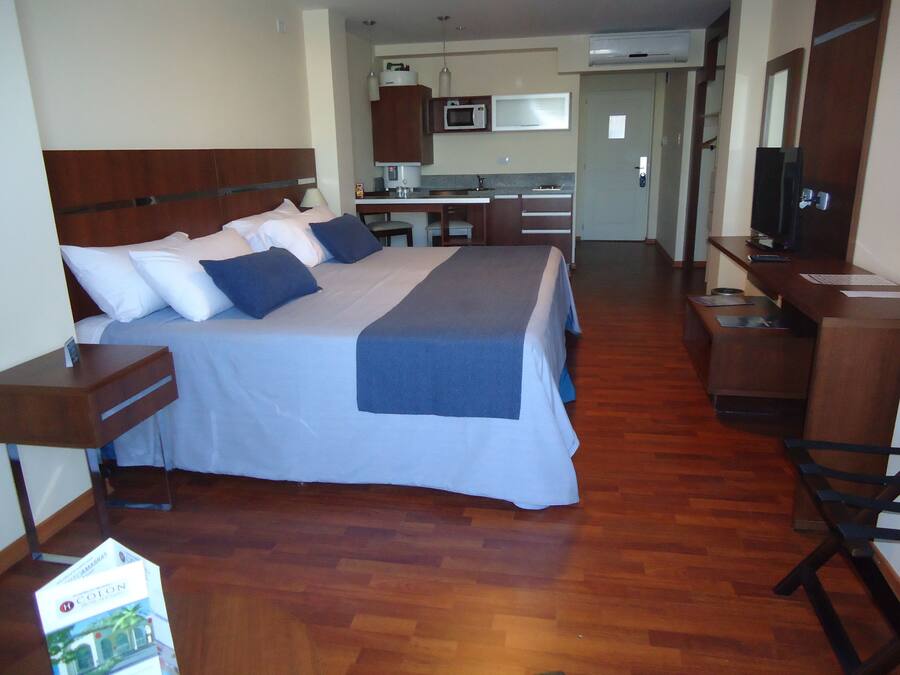 Una habitación de hotel con una cama grande, un escritorio, una silla, un microondas y un televisor.