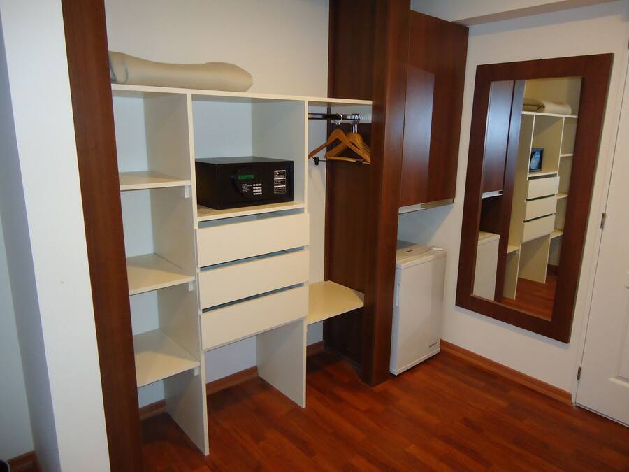 Um closet amplo com prateleiras de madeira, um eletrodoméstico branco e um espelho.