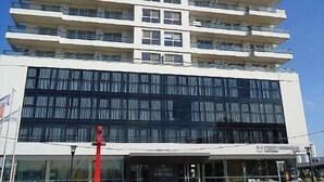 Un hotel de varios pisos con una fachada moderna, amplias ventanas y una tienda visible a nivel de calle.
