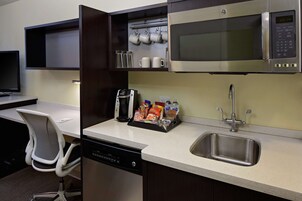 Una cocina compacta equipada con microondas, lavamanos y cafetera.