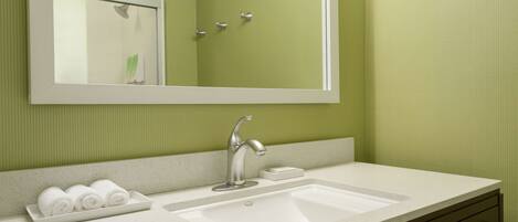 A bathroom with a white sink, a mirror, and a green wall.