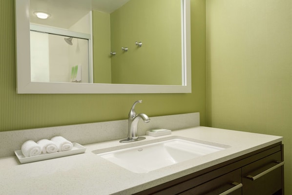 Un baño con un lavabo blanco, un espejo y una pared verde.