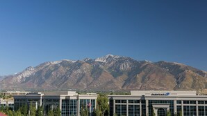 A modern building with a Dealertrack sign, surrounded by trees and mountains in the background. - Home2 Suites by Hilton Salt Lake City/South Jordan, UT (South Jordan)