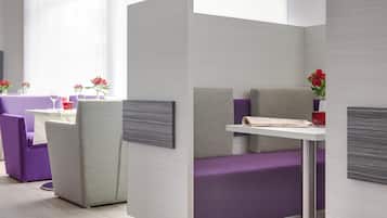 A modern hotel room with a minimalist design, featuring a purple and grey color scheme, a white table, and a comfortable seating area.