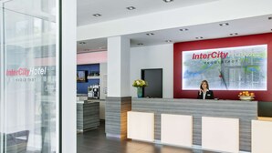 A modern hotel reception area with a large digital map display, a reception desk, and a seating area with a glass partition. - IntercityHotel Ingolstadt (Ingolstadt)