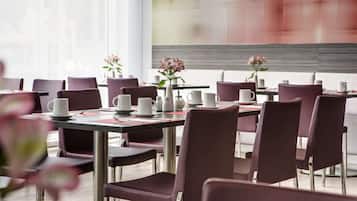 A modern dining area with purple chairs and tables, each set with white cups and a vase of flowers.