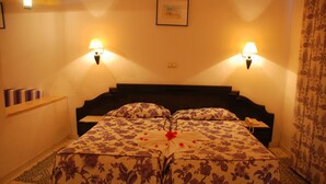 A hotel room with a bed, two wall-mounted lamps, a framed picture, and a patterned curtain. - Joya Paradise (Djerba Midun)