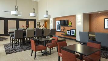 A hotel lobby with a reception desk, seating area, and a television mounted on the wall.