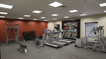 A gym with treadmills, weight machines, and dumbbells.