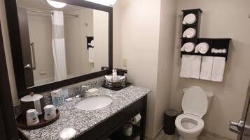 A bathroom with a sink, mirror, towel rack, toilet, and a trash bin.