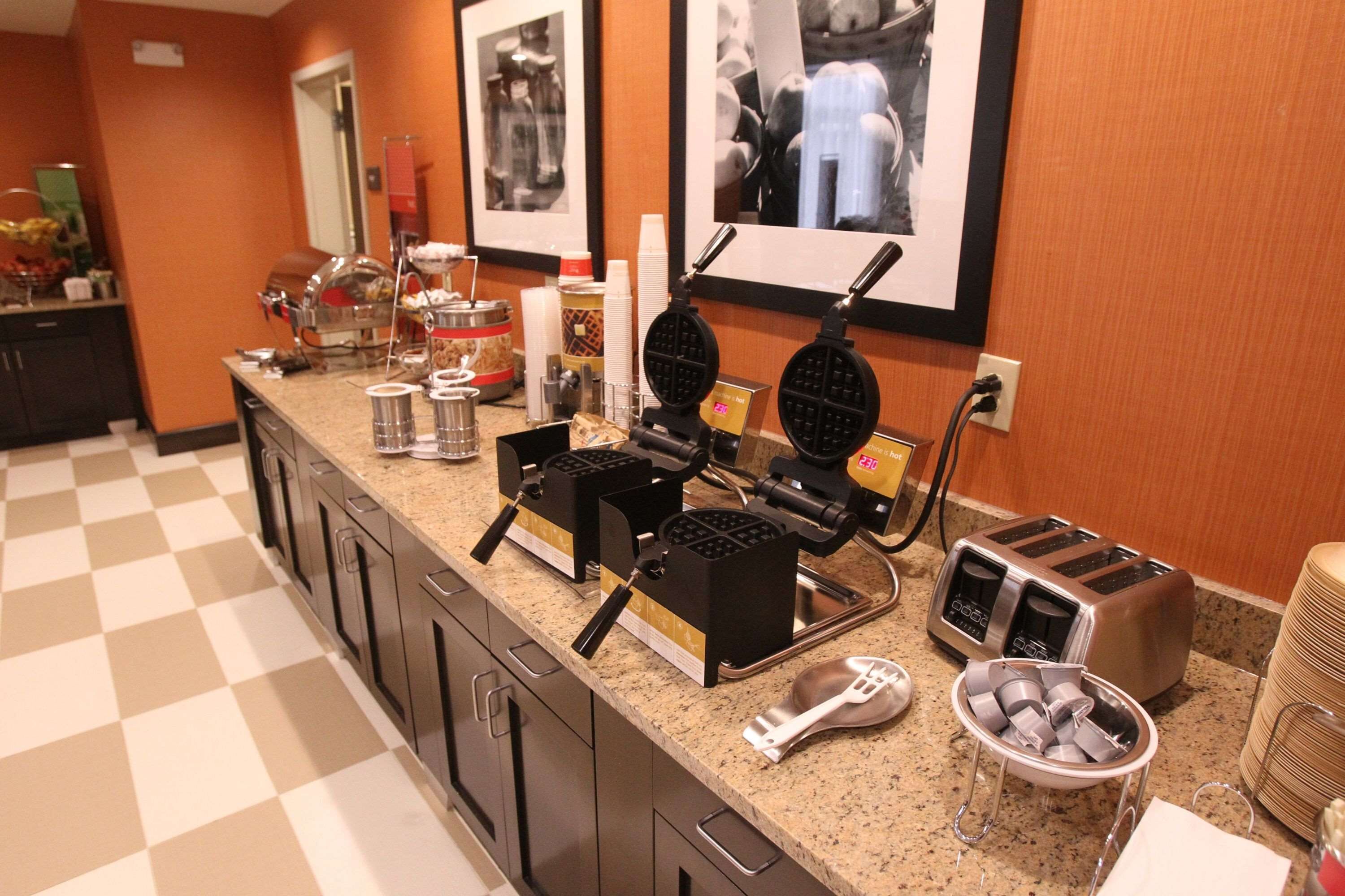 A kitchen counter with waffle makers, a toaster, and various condiments.