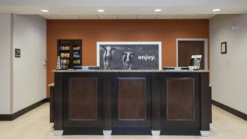 A reception desk with a framed picture of a cow and the word "enjoy." on the wall behind it.
