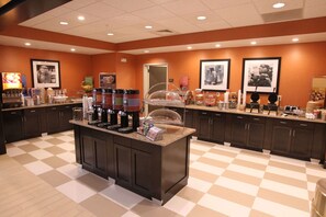 A breakfast bar with a checkered floor, a coffee station, and framed pictures on the walls. - Hampton Inn & Suites Seneca-Clemson Area (Seneca)