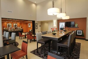 Une salle à manger d’hôtel avec une longue table, de nombreuses chaises et un bar en arrière-plan.
