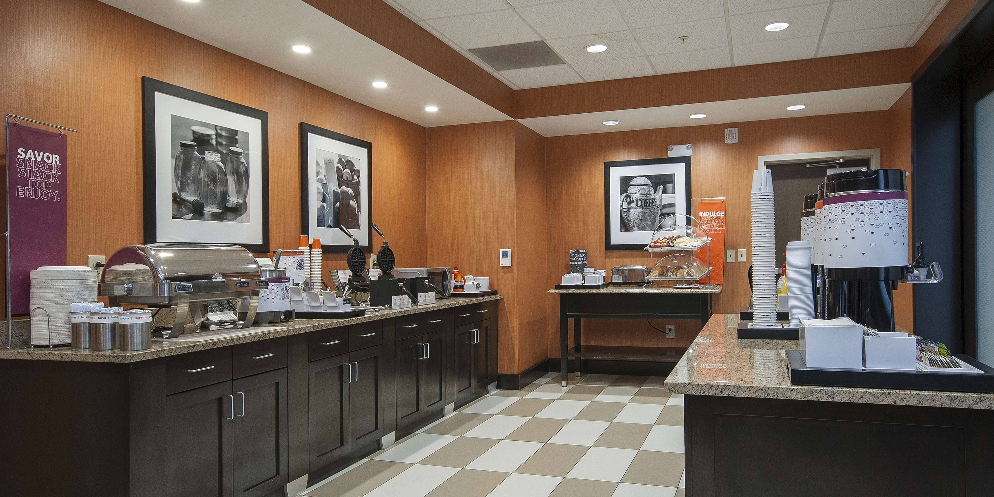 A hotel kitchen with a buffet setup, including a coffee machine, food dispensers, and a coffee station.