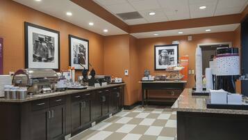Una cocina de hotel con un montaje tipo bufé, que incluye una máquina de café, dispensadores de alimentos y una estación para café.
