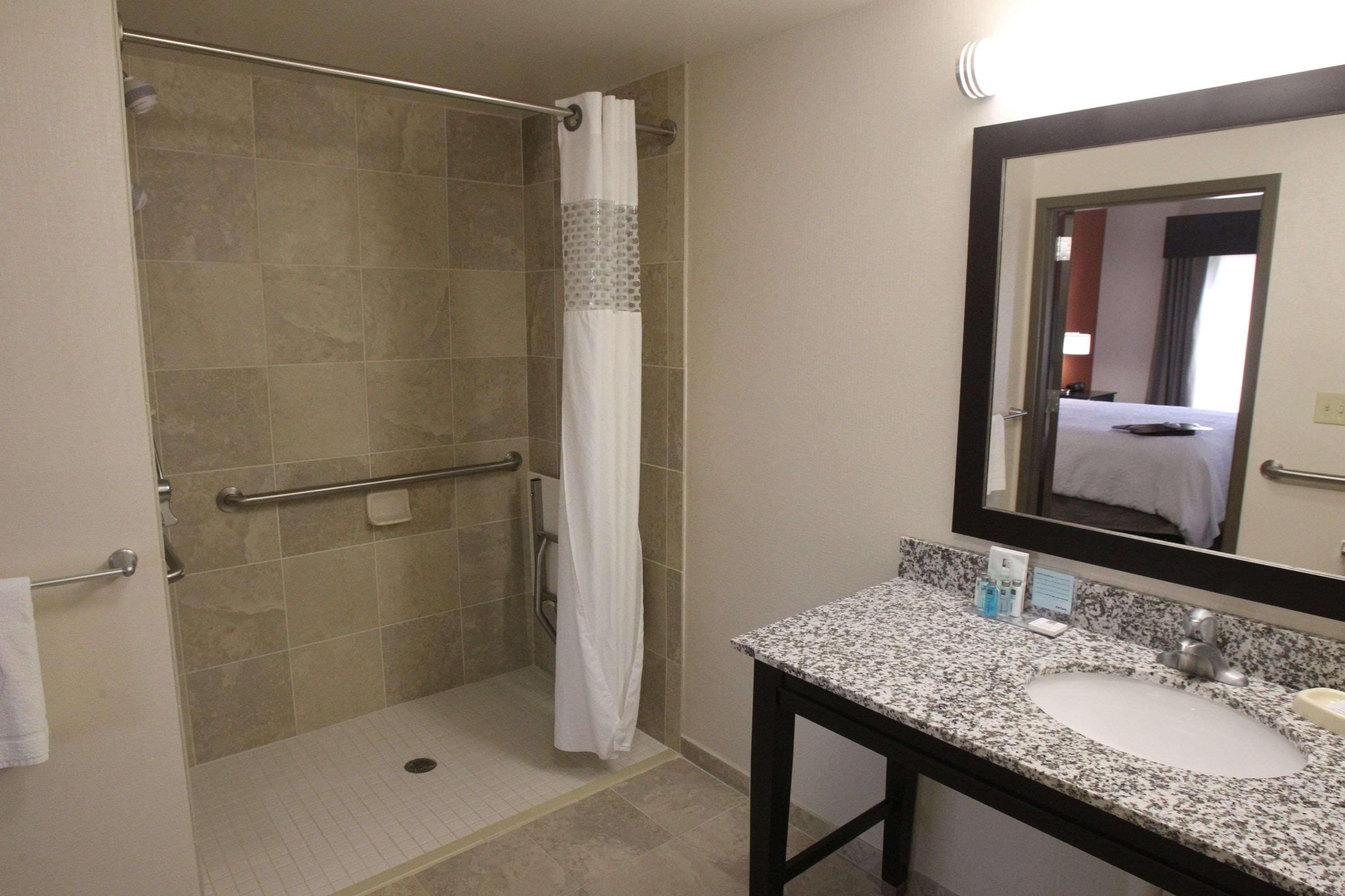 A bathroom with a shower, a sink, and a mirror.