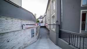 A narrow alleyway with a parking sign, a building with a white facade, and a metal railing. - Hotel Jakob Regensburg DownTown, BW Signature Collection (Regensburg)