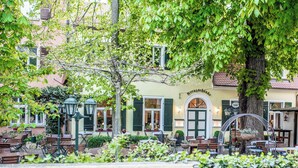 An outdoor cafe with tables and chairs, surrounded by greenery and a building with a sign reading "Kreuzschanke". - Hotel Jakob Regensburg DownTown, BW Signature Collection (Regensburg)